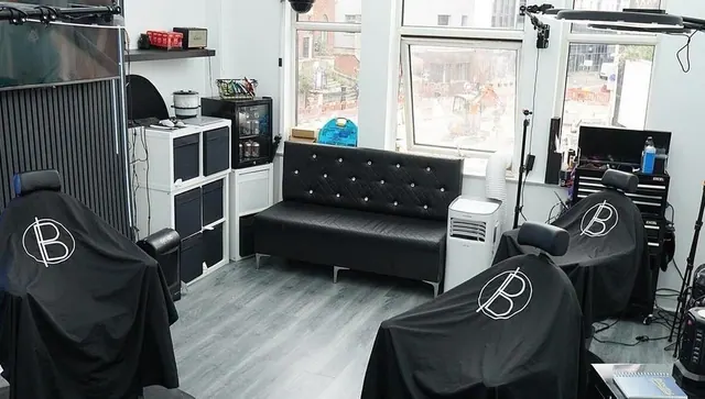 Inside the shop: a studded black sofa by the window and a barber chair